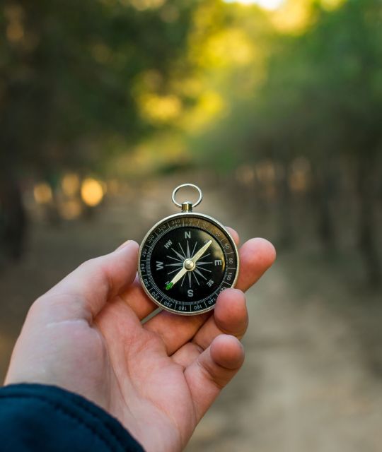 Compass in the mountains Hand with compass at mountain road at sunset sky